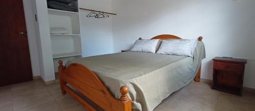 ein Schlafzimmer mit einem Bett mit einem hölzernen Kopfteil in der Unterkunft Chalet a 500mts del mar in Mar del Tuyú