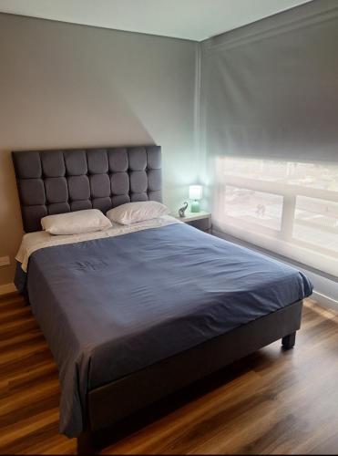 a large bed in a bedroom with a large window at Loft centro internacional in Bogotá
