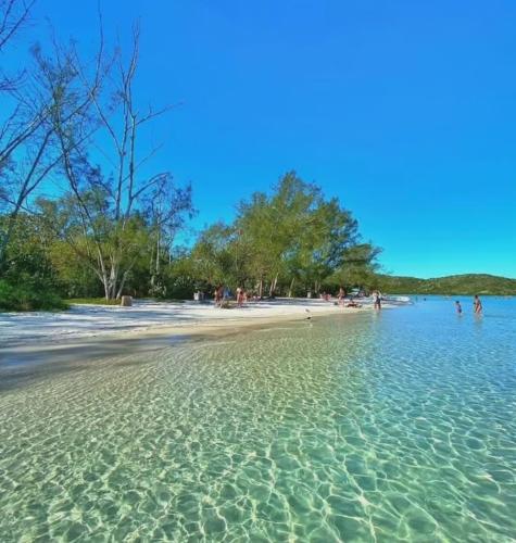 a beach with a bunch of people in the water at Maravilha de Peró in Cabo Frio