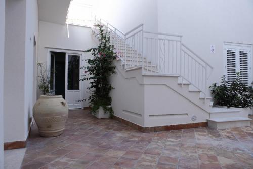 a white staircase in a white room with plants at Aegusa Hotel in Favignana