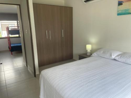 a bedroom with a white bed and a wooden cabinet at Santa Monica Beach House in El Chirú