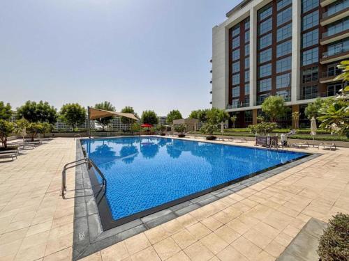 a large swimming pool in front of a building at Tranquil 1 Bedroom Dubai Hills Escape in Dubai