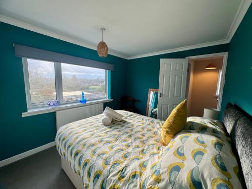 a bedroom with a bed with blue walls and a window at St Martin’s view in Haverfordwest