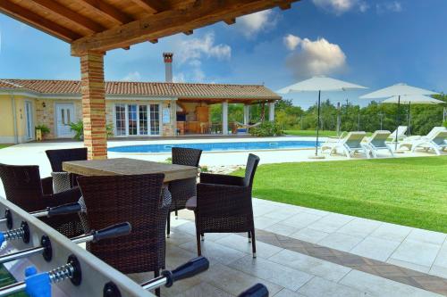 Un patio con mesa y sillas y una piscina. en Villa Manuela by Rent Istria, en Babići