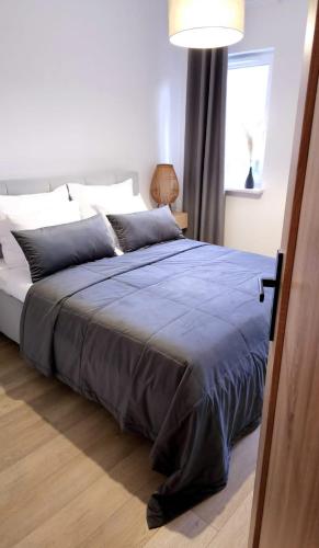 a bedroom with a large bed with a blue blanket at Apartament Stary Tartak in Ostróda