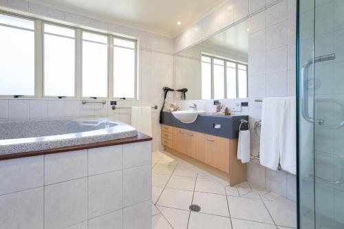 a bathroom with a tub and a sink at Regal Palms Resort in Rotorua