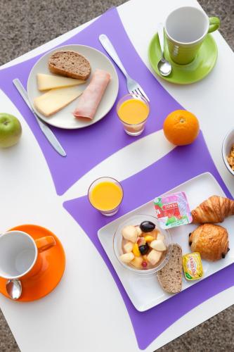 a purple table with plates of food and cups of coffee at ibis Styles Roanne Centre Gare in Roanne