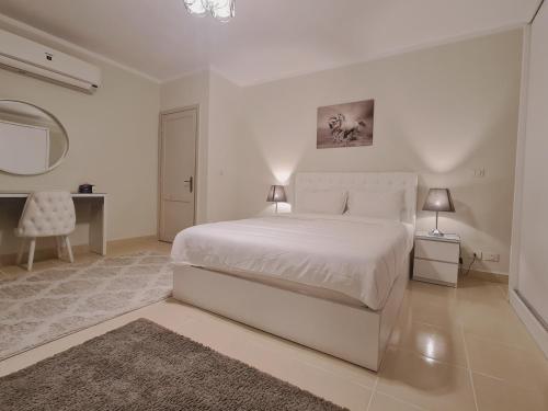 Biała sypialnia z białym łóżkiem i biurkiem w obiekcie El Rehab, 3 BR Apt Garden view Sweet Homies w mieście New cairo