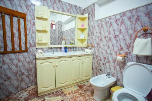 un bagno con lavandino, WC e specchio di Klevi Apartment a Tirana