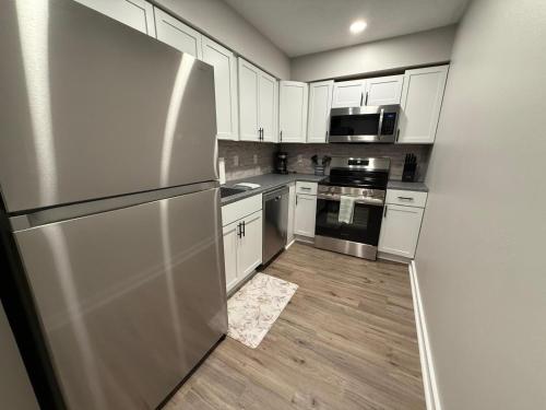 a kitchen with white cabinets and a stainless steel refrigerator at Central to Zoo and Baxter Arena, Pet Friendly in Omaha
