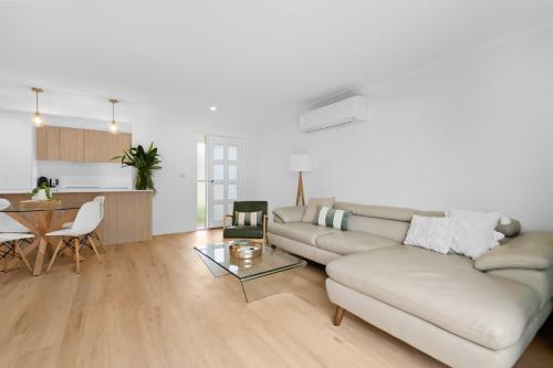 a living room with a couch and a table at Banksia Breeze Villa - 100m to North One Mile Beach & Pet Friendly in Forster