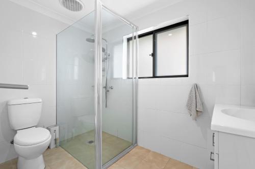a bathroom with a glass shower stall and a toilet at Banksia Breeze Villa - 100m to North One Mile Beach in Forster