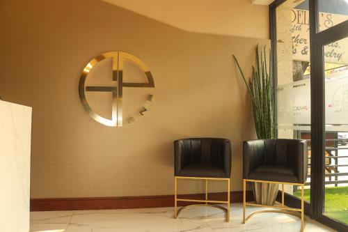 two black chairs sitting next to a wall with a mirror at Hotel Grand One Plaza in Tijuana