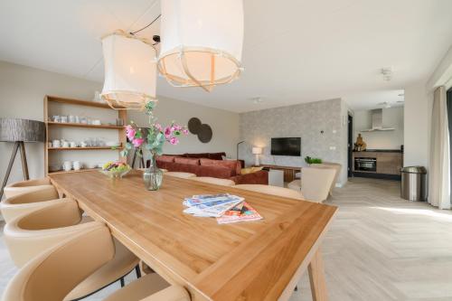a dining room and living room with a wooden table and chairs at Aan Het Water 'Wetterhaghe' optioneel met E-Sloep in Heeg