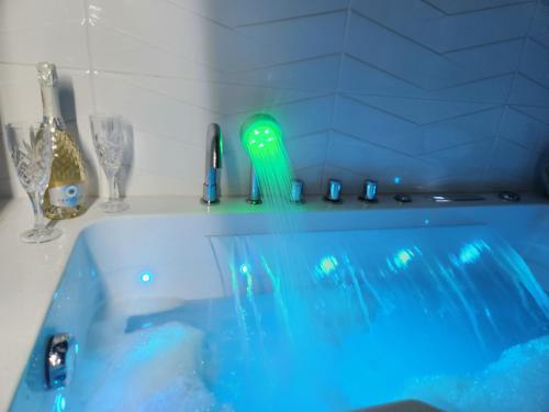 a blue bath tub with glasses and a green faucet at New! Warsaw Luxury Apartment with Jacuzzi and total relax - Warszawski Luksus Jacuzzi i totalny relaks! in Warsaw