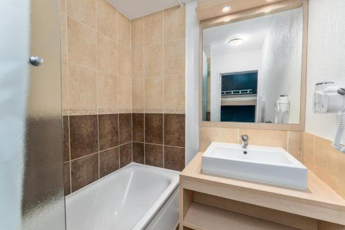 une salle de bain avec un lavabo, une baignoire et un miroir dans l'établissement Résidence Les Terrasses Du Soleil D'or - Chaleureux appartement aux portes des pistes MAE-6544, aux Orres