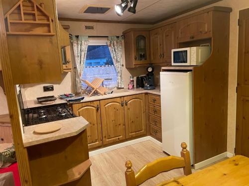 une cuisine avec des armoires en bois et un réfrigérateur blanc dans l'établissement Mobilhome des Quatre Terres, à Lesparre-Médoc