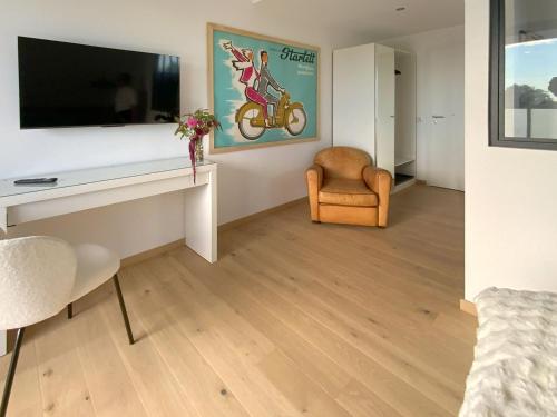 Il comprend un salon doté d'un bureau, d'une télévision et d'une chaise. dans l'établissement L'escapage Vintage - Gîte - 2 chambres, à Eschau