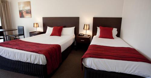 a hotel room with two beds with red pillows at Mercure Port of Echuca in Echuca