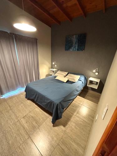 a bedroom with a bed with two tables and a window at Departamentos Norte 2 in Villa Gesell