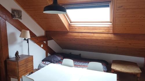 une chambre mansardée avec un lit et une fenêtre dans l'établissement charmant t2 montagne, à Saint-Hilaire