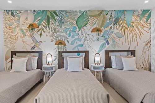 2 Einzelbetten in einem Zimmer mit Wandbild in der Unterkunft Beachfront - Flamingo Luxury 2BR condo - E423 in Palm-Eagle Beach