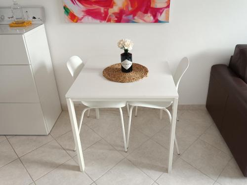 a white table with two chairs and a vase with flowers at A casa di Pizz - Bilocale con parcheggio privato in Savona