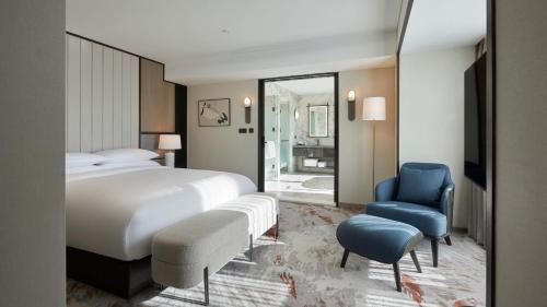 a bedroom with a large bed and a blue chair at Grand InterContinental Seoul Parnas by IHG in Seoul