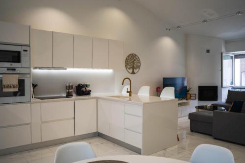 a kitchen with white cabinets and a living room at Casa Terra Mar in Angra do Heroísmo