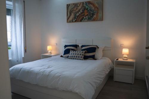 ein Schlafzimmer mit einem Bett mit Kissen und zwei Lampen in der Unterkunft Casa Terra Mar in Angra do Heroísmo