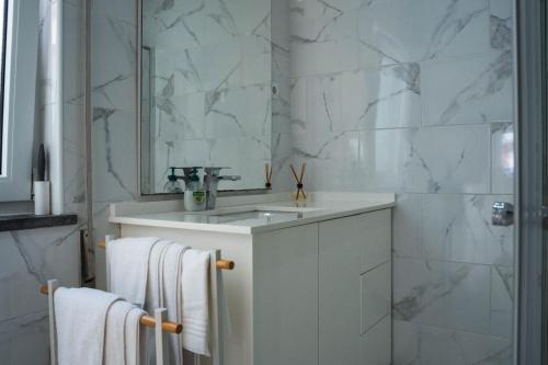 ein weißes Badezimmer mit Waschbecken und Spiegel in der Unterkunft Casa Terra Mar in Angra do Heroísmo