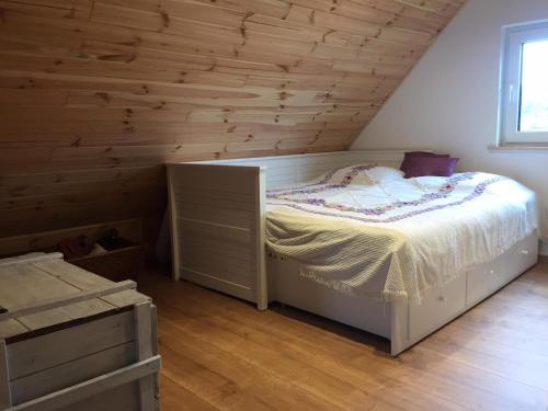 a bedroom with a bed and a wooden wall at Domek Walentinki in Rogacze