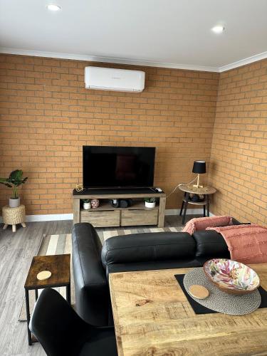 a living room with a couch and a flat screen tv at Lbarza Modern 1BR Apartment close to CBD in Shepparton