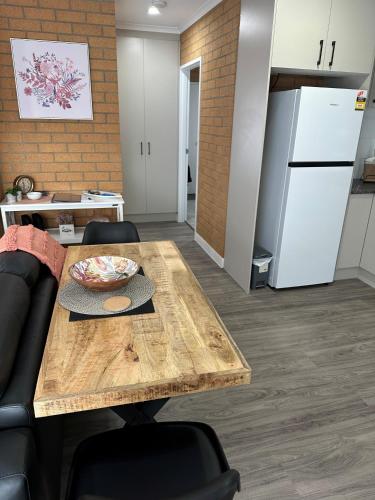 a kitchen with a wooden table and a refrigerator at Lbarza Modern 1BR Apartment close to CBD in Shepparton