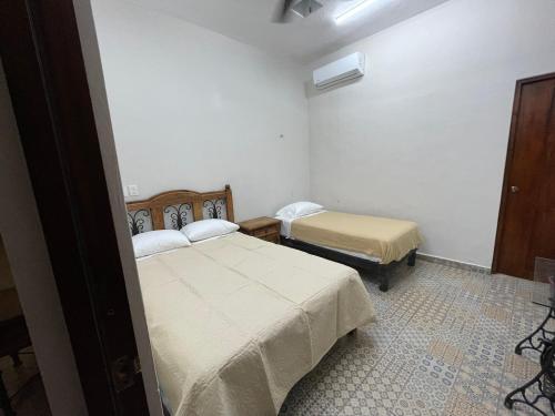 a small room with two beds and a chair at My Family In Merida Hostel in Mérida