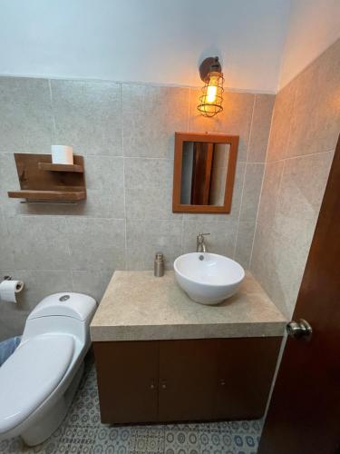 a bathroom with a white toilet and a sink at My Family In Merida Hostel in Mérida