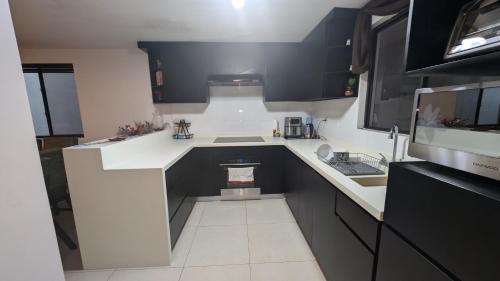 a small kitchen with black and white cabinets and a sink at Everest 663 in Monterrey