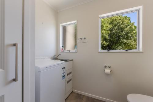 a white bathroom with a sink and a window at Linkwater Wonder - Marlborough Holiday Home in Picton