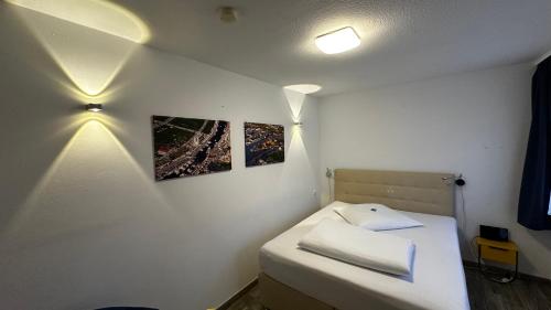 Una cama pequeña en una habitación con dos cuadros en la pared. en Hotel Zierow - Urlaub an der Ostsee, en Wismar