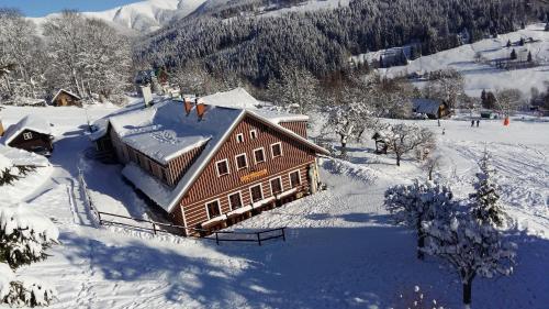 a large wooden building covered in snow at U Novotných in Špindlerův Mlýn