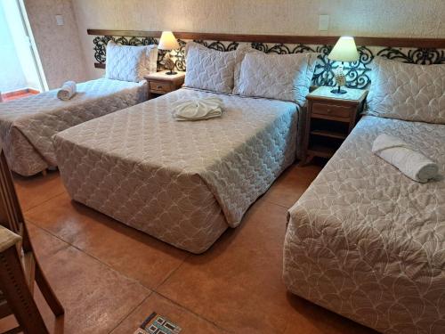 a hotel room with two beds and two tables at Pousada Brasil Nativo in Cabo Frio