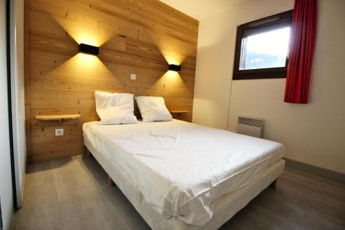 une chambre avec un grand lit avec un mur en bois dans l'établissement Résidence Les Balcons De La Vanoise - LES BALCONS DE LA VANOISE -BV410 MAE-6781, à Villarodin-Bourget