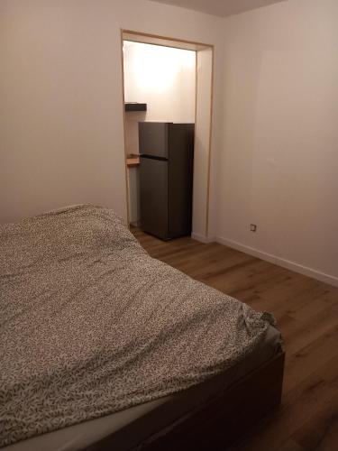 Schlafzimmer mit einem Bett und einem Kühlschrank in der Unterkunft Hébergement Cozy à Deville-lès-Rouen - 13 min Rouen in Déville-lès-Rouen