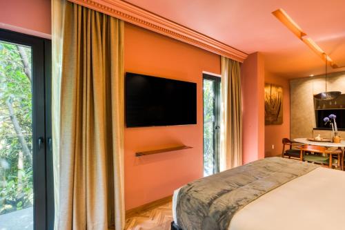 a bedroom with an orange wall with a flat screen tv at El Alfonsa in Mexico City