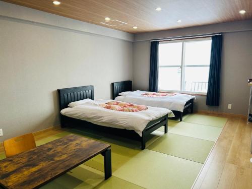 a room with two beds and a table and a window at Hotel Japan Shiga in Yamanouchi