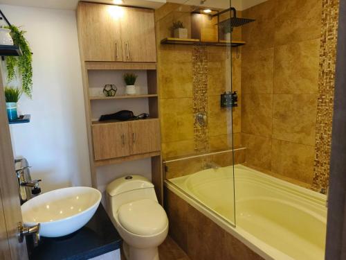 a bathroom with a toilet and a tub and a sink at Hope Aparta Lofts in Salento