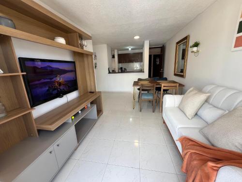 a living room with a white couch and a flat screen tv at Piso 11 con vista a la montaña, Callejuelas in Piedecuesta