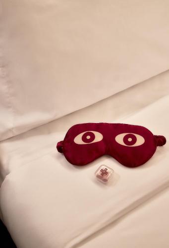 a red mask laying on top of a bed at Now Now NoHo in New York