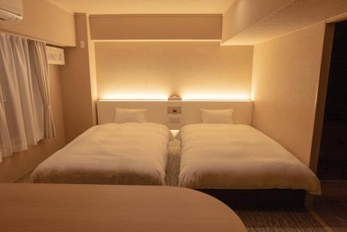 two beds in a small room with lights at Hotel Alpha Inn Akita in Akita