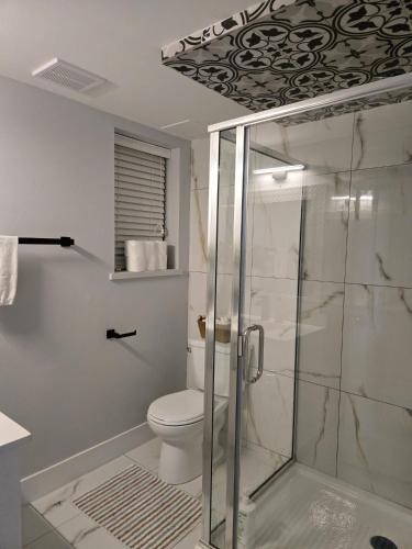 a bathroom with a toilet and a glass shower at A new luxury basement apartment in Surrey